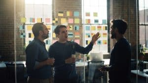 A frontend team planning a Hyva migration on sticky notes across a glass wall in a Brooklyn studio
