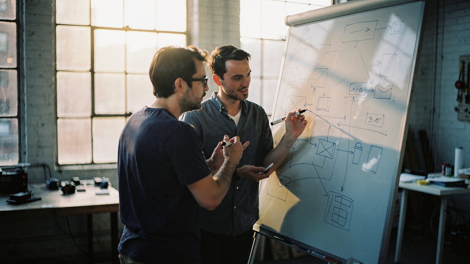 Two engineers working through a stalled Magento build at a whiteboard in a Brooklyn studio