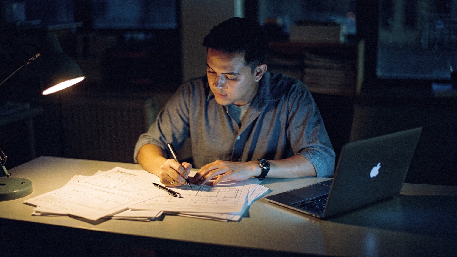 Engineer reviewing a printed Magento 1 to Magento 2 migration plan beside a laptop in a quiet Brooklyn office
