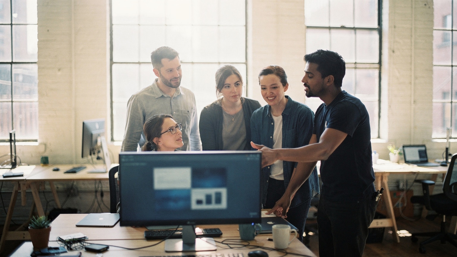 A new agency team being walked through a Magento store by a client lead at a shared screen in a Brooklyn office