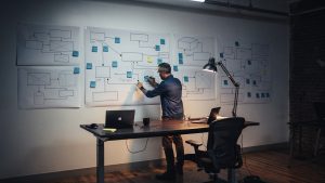 Ecommerce engineer mapping a printed sitemap and 301 redirect diagram on a wall in a Brooklyn agency